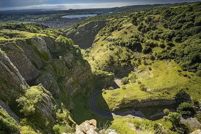 Looking down into Cheddar Gorge, with the road winding between grassy limestone cliffs