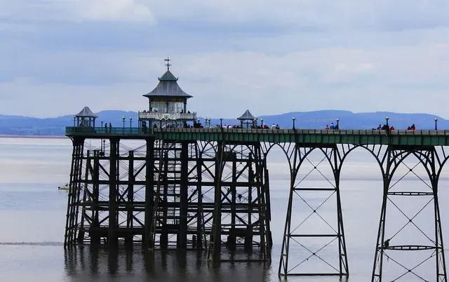 The slender arched spans of Clevedon Pier leading out to its pier head over a calm Severn Estuary