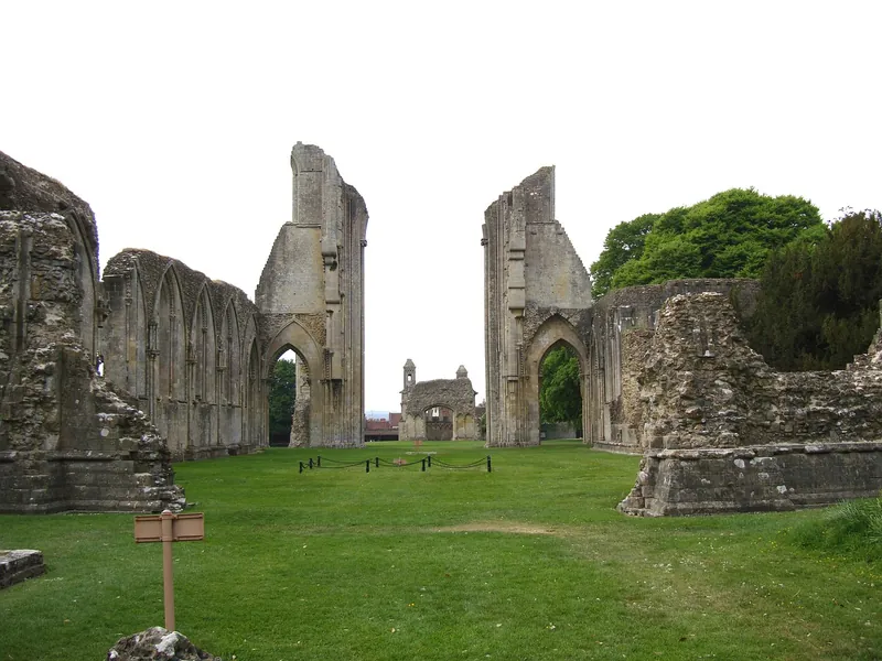 The ruined stone arches of Glastonbury Abbey standing over a wide lawn