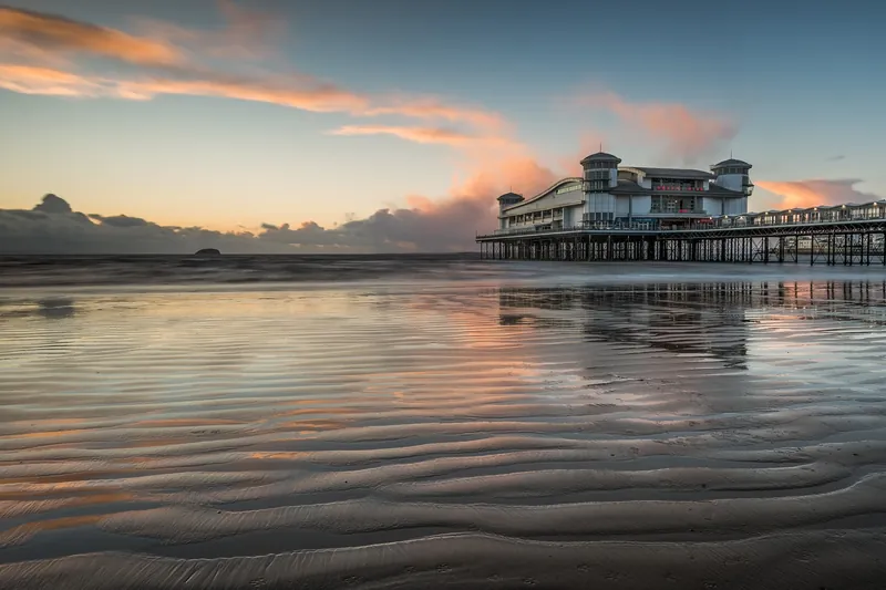 The Grand Pier at Weston-super-Mare at sunset, reflected in the wet sand at low tide