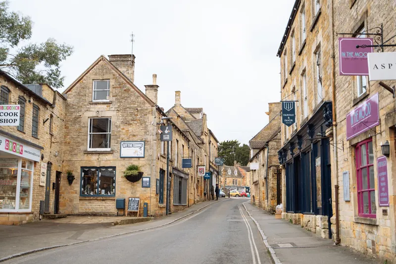 A quiet street of honey-stone buildings and small independent shops in an English country town